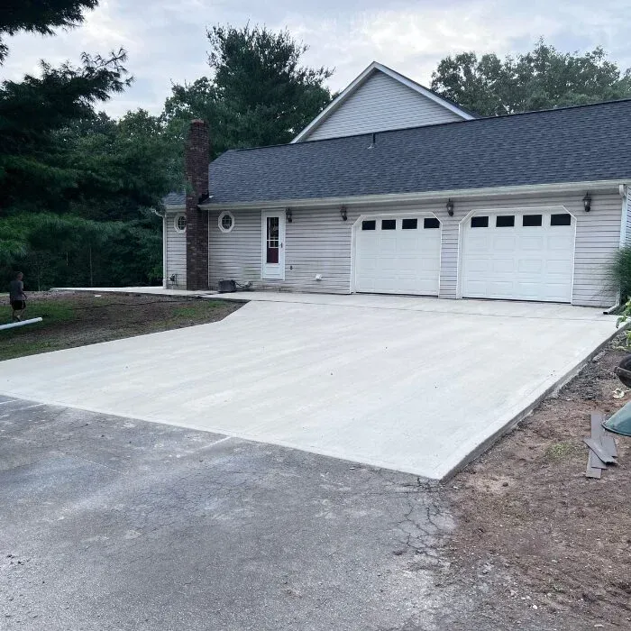 New gray concrete driveway leading to a two-car attached garage