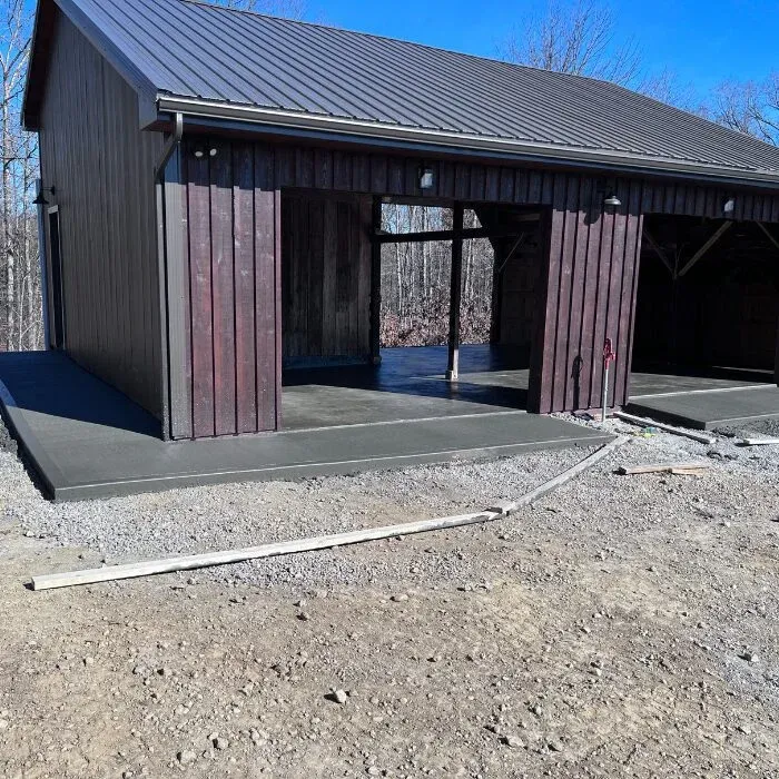 Concrete apron and pad poured around the entrances of a dark pole barn