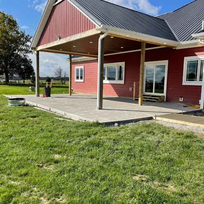 Stamped concrete patio under a covered porch at a red farmhouse
